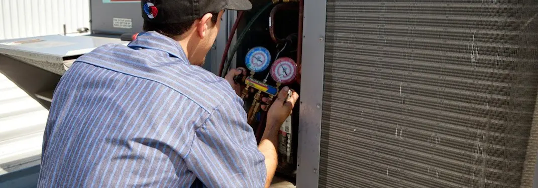 HVAC technician servicing a condenser unit in Bath
